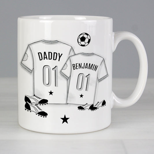 Mug with T-shirt print with personalised name. 1 large T-shirt and 1 small T-shirt with football and football boots in background.