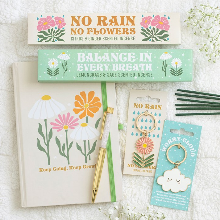 Set of incense sticks with floral packaging, notebook and pen and 2 styles of keyrings on a white background