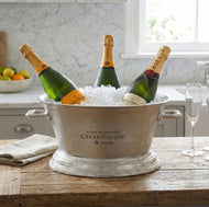 Three bottles of champagne in a metal ice bucket on a wooden table.