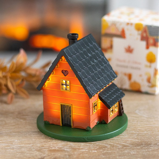 Small decorative house with a black roof on a wooden surface