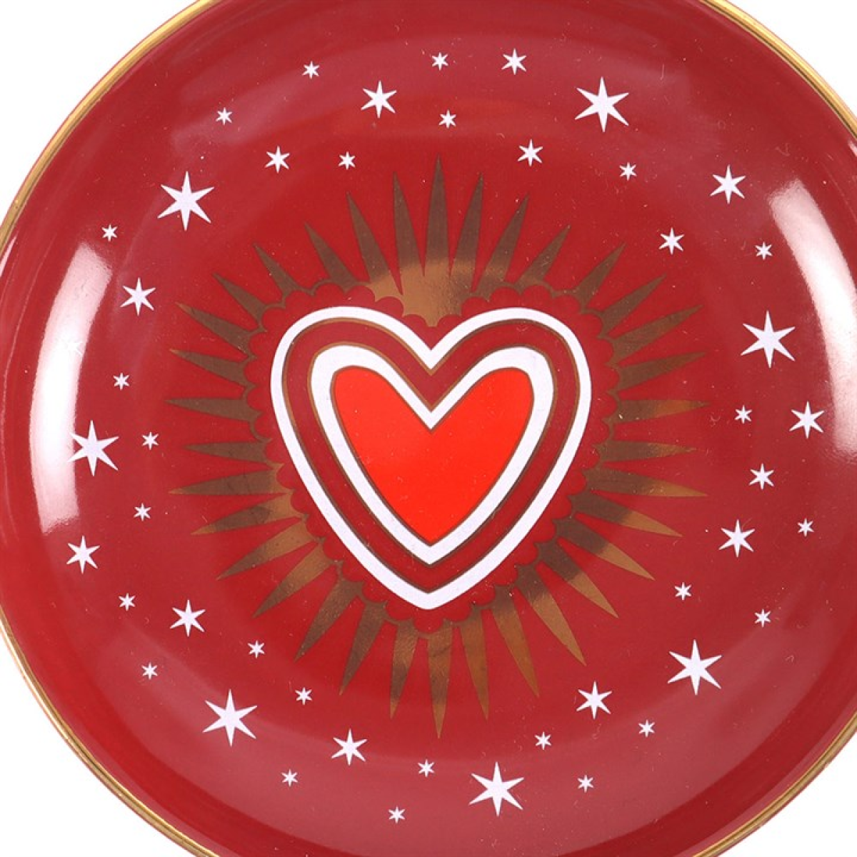 Red trinket dish with a central heart design and star patterns on a white background