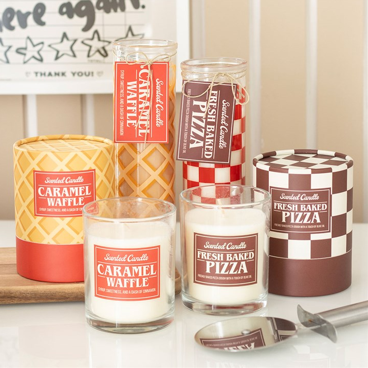 Collection of candles with labels indicating flavors and brand name on a white surface.