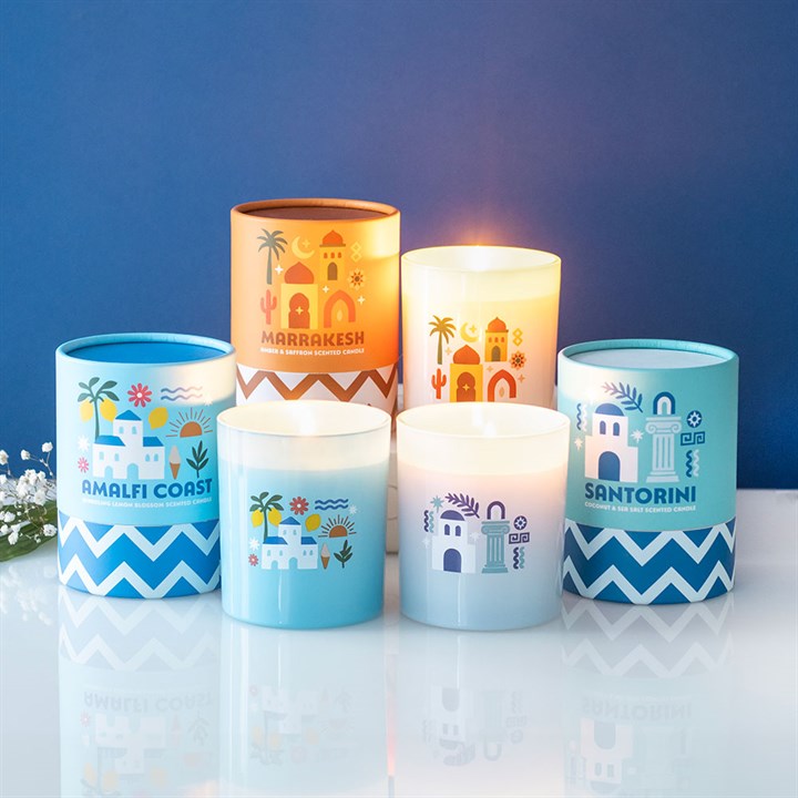 Set of decorative candles with travel themed designs on a reflective surface against a blue background