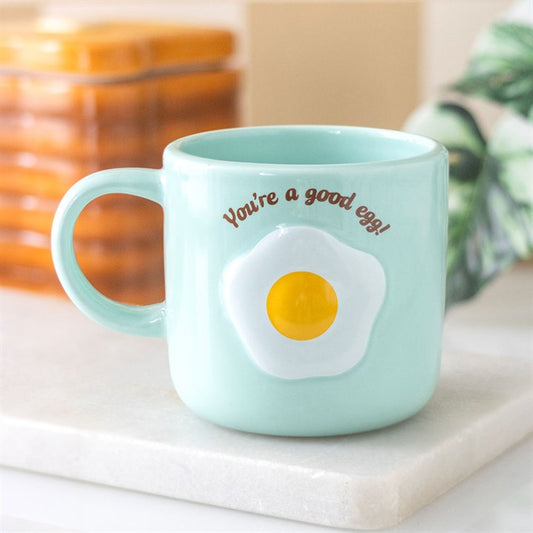 Light blue mug with an egg design and text 'You're a good egg!' on a white surface.