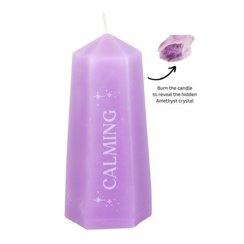 A purple candle shaped like a crystal tower with the word 'CALMING' printed on its side. An amethyst crystal is shown beside the candle, indicating the hidden crystal inside.