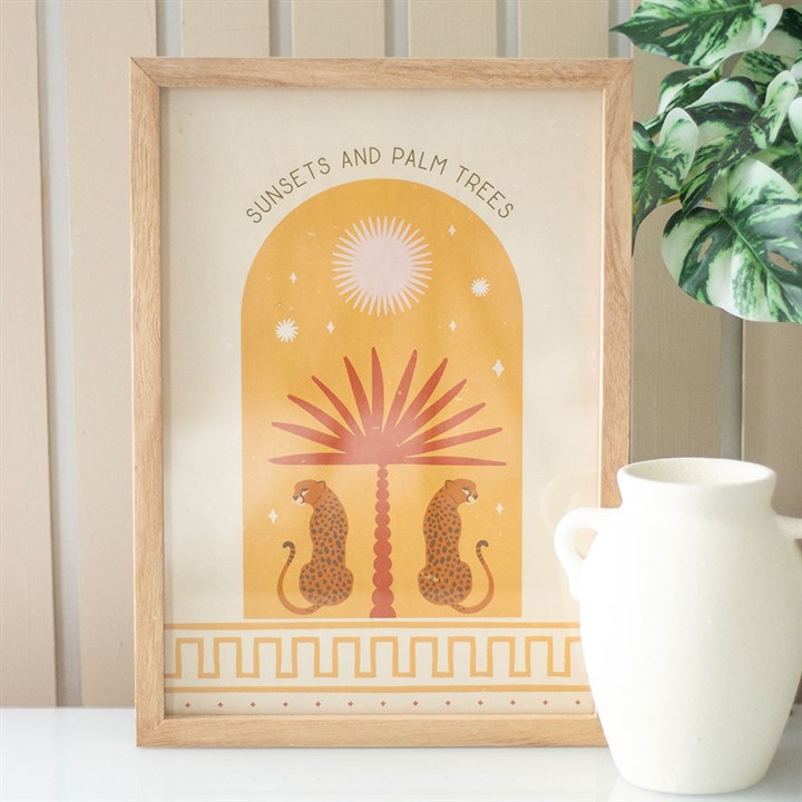 A framed wall art print featuring a design of two leopards lounging beneath a palm tree, with the text 'Sunsets and Palm Trees' at the top.