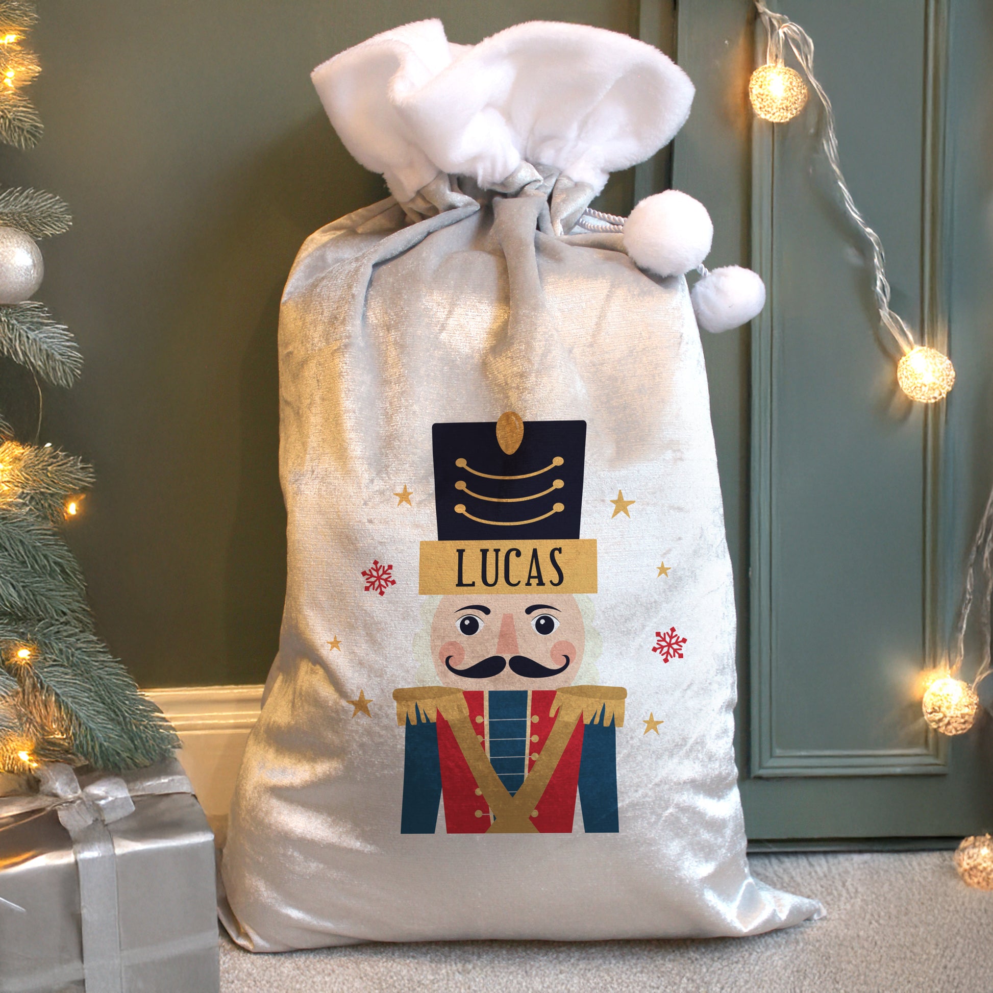 Personalised Christmas sack with a nutcracker design and the name 'Lucas', placed against a festive background with lights and a tree.