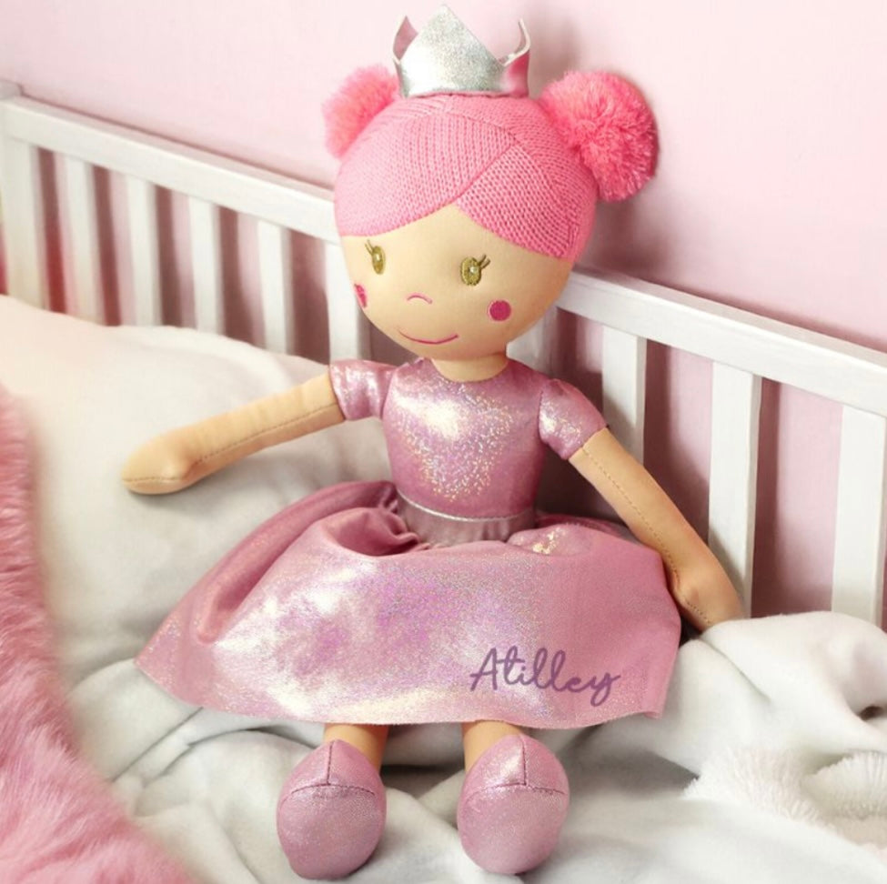 Stuffed doll with pink outfit and crown on a crib