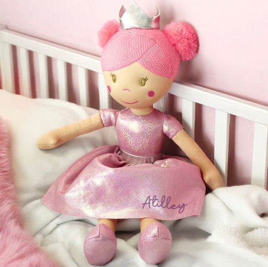Stuffed doll with pink outfit and crown on a crib