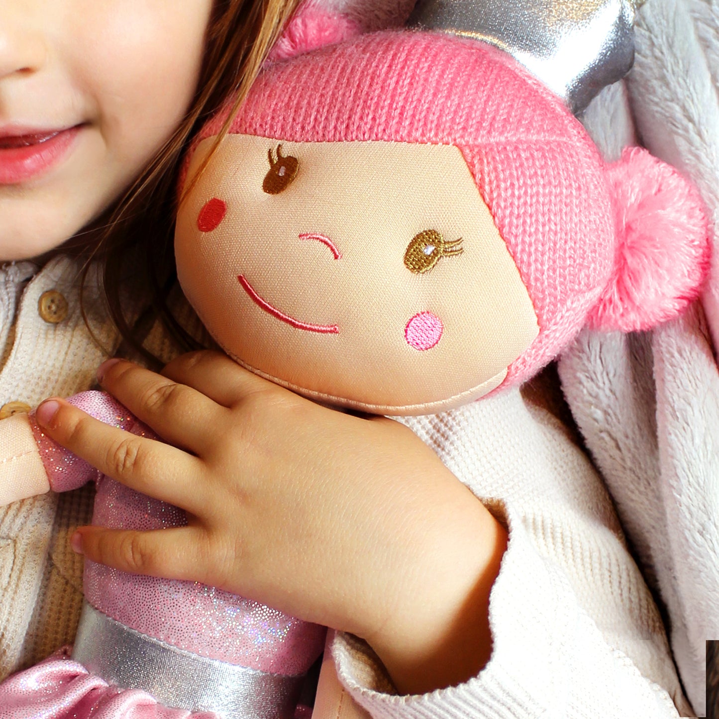Child holding a plush toy with a pink hair and smiling face
