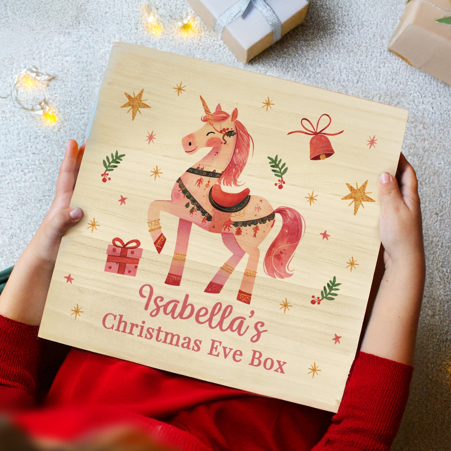 Wooden Christmas Eve box with a unicorn design and 'Isabella's Christmas Eve Box' text, held by hands.