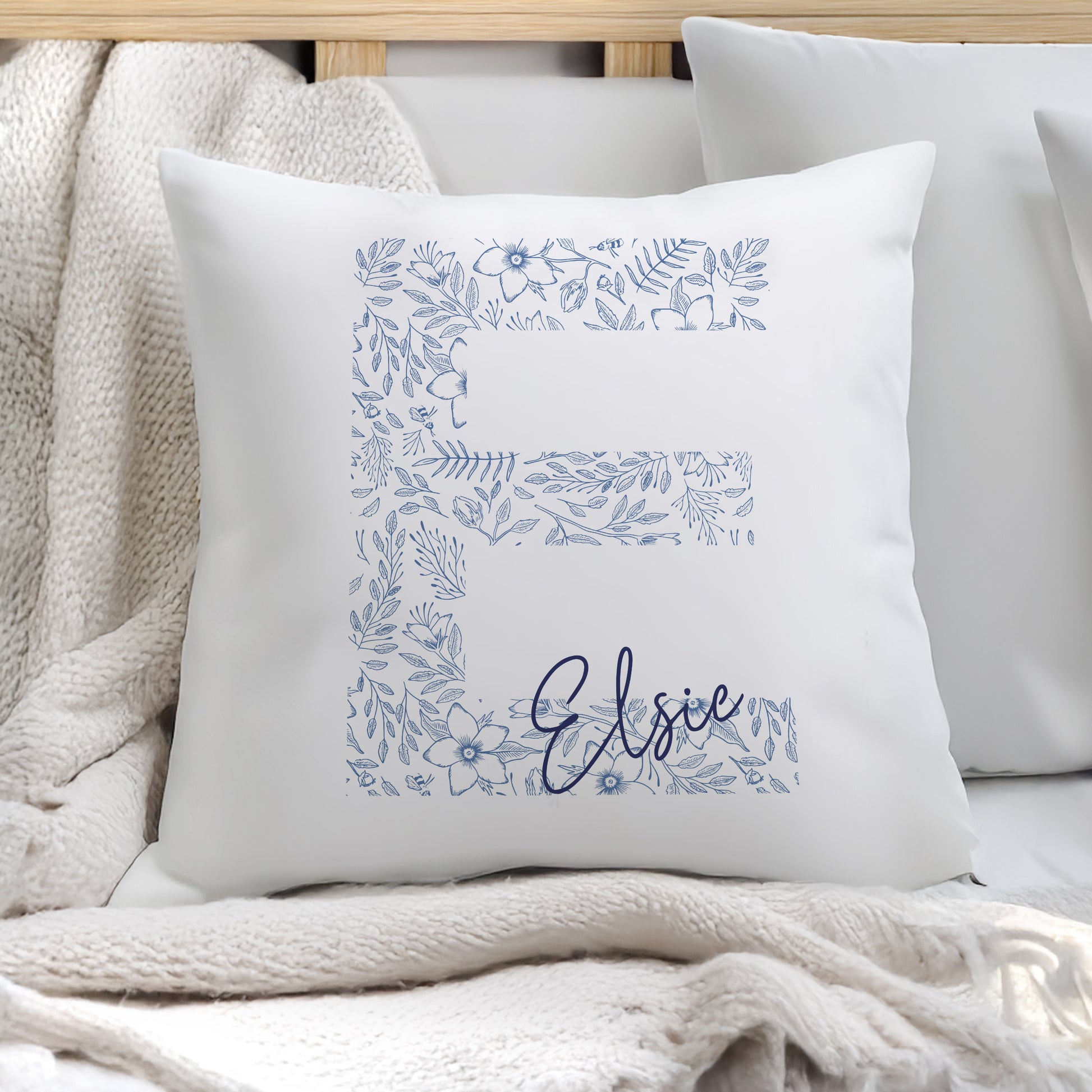White pillow with blue floral patterns and 'Elsie' text on a soft surface.