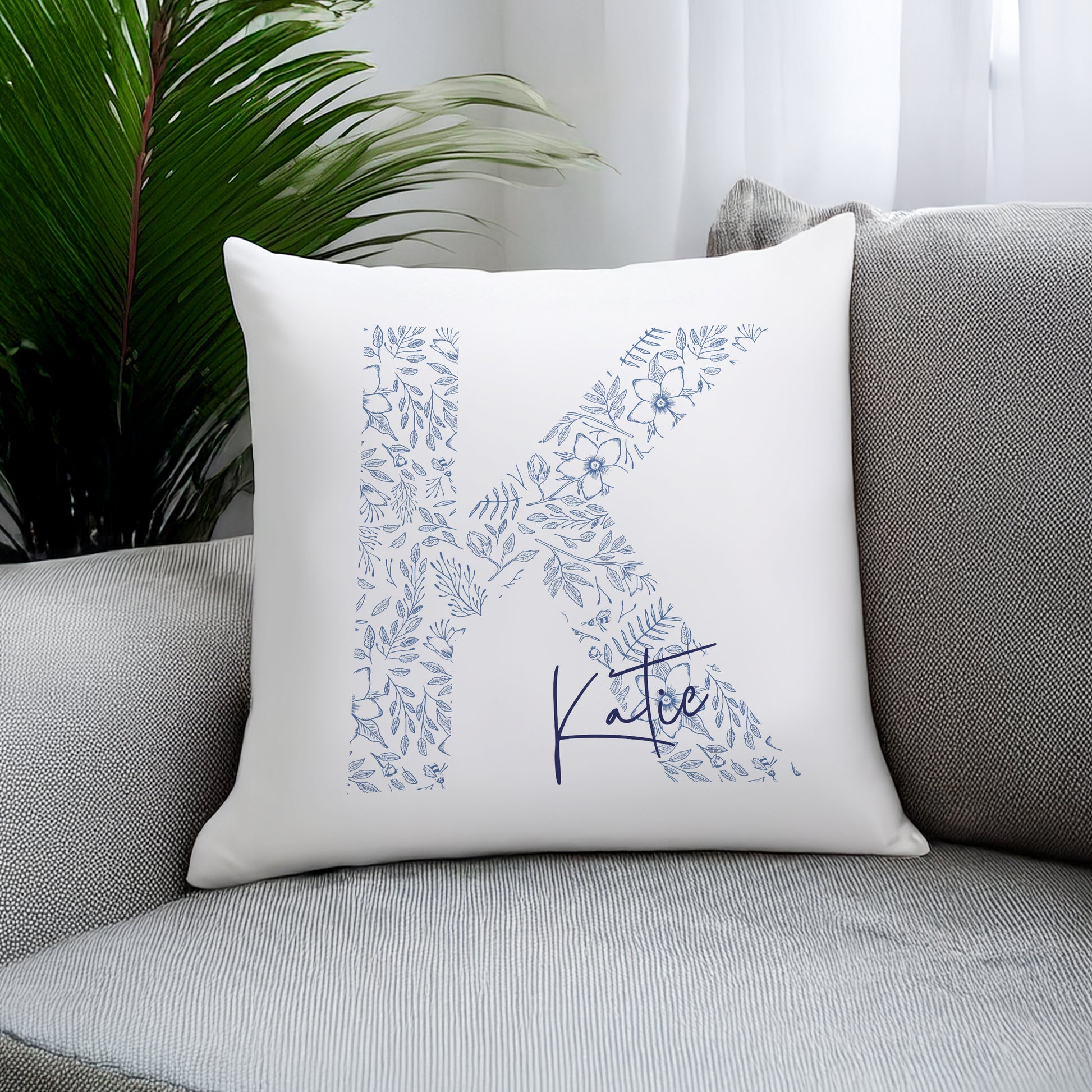 Decorative pillow with floral letter 'K' and name 'Katie' on a gray couch.