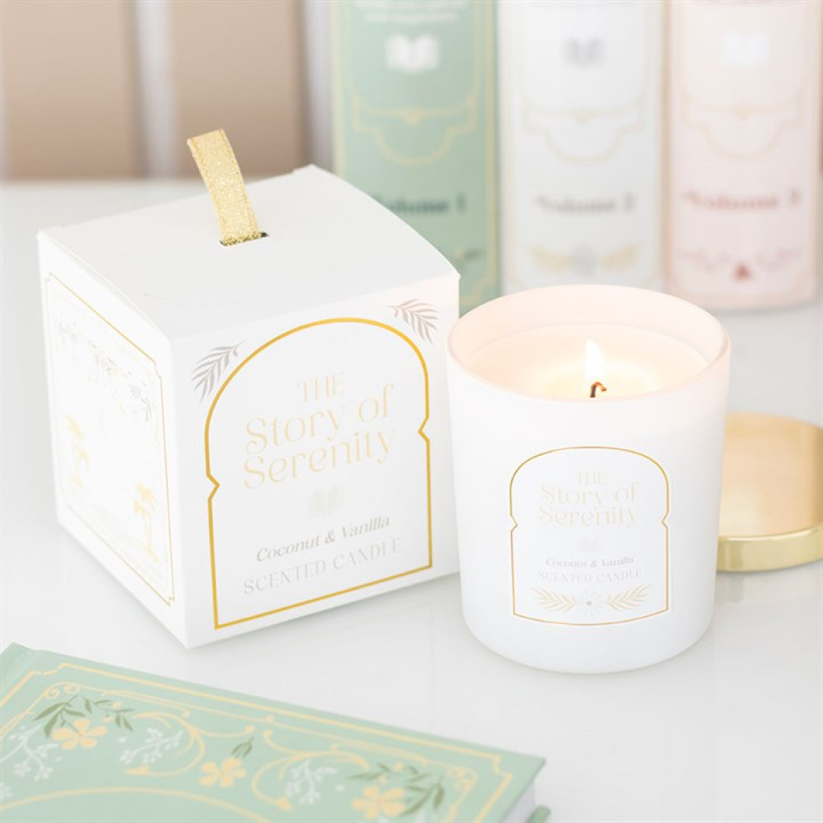 White candle with gold text next to its packaging on a white surface