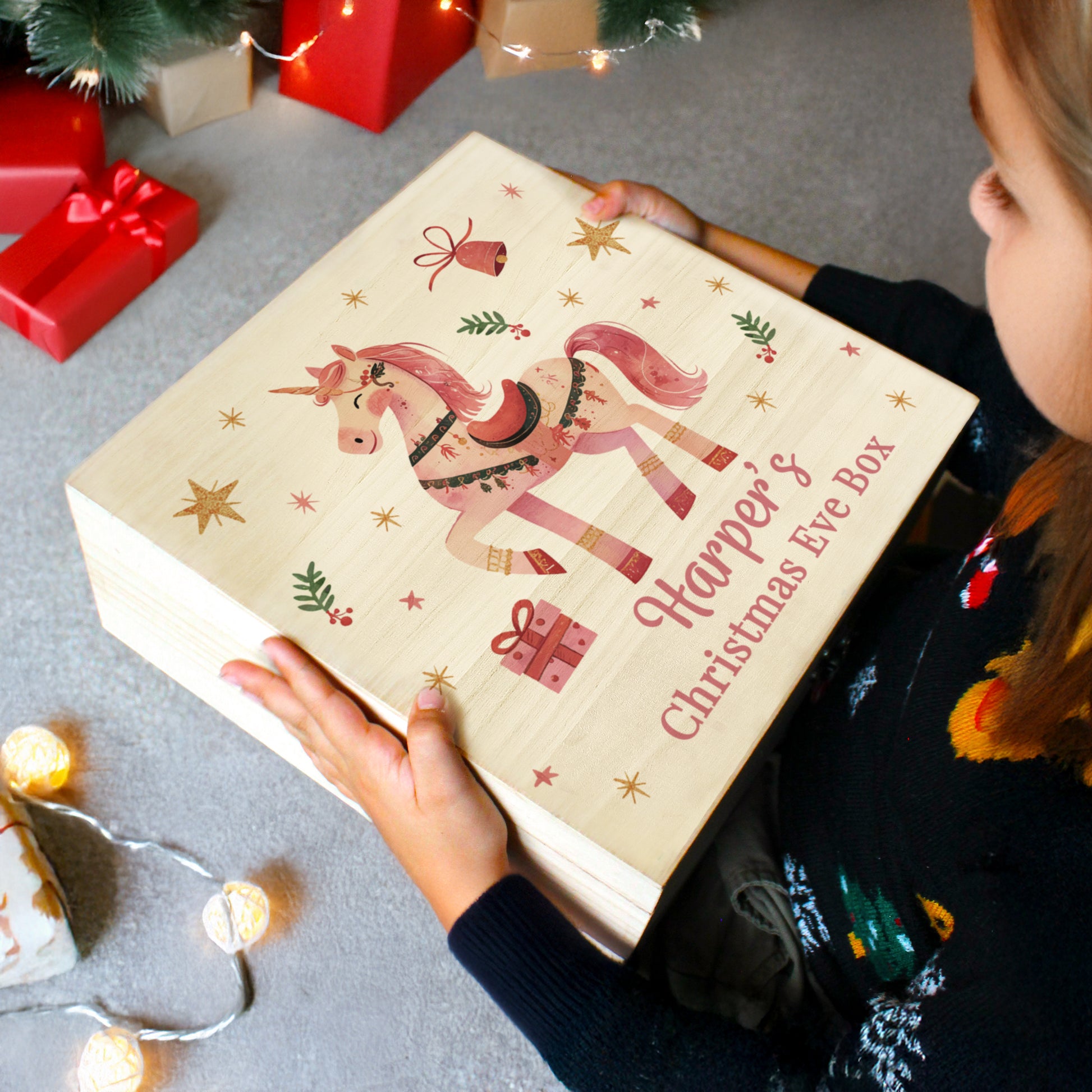 Child holding a Christmas Eve box with a unicorn design and text.