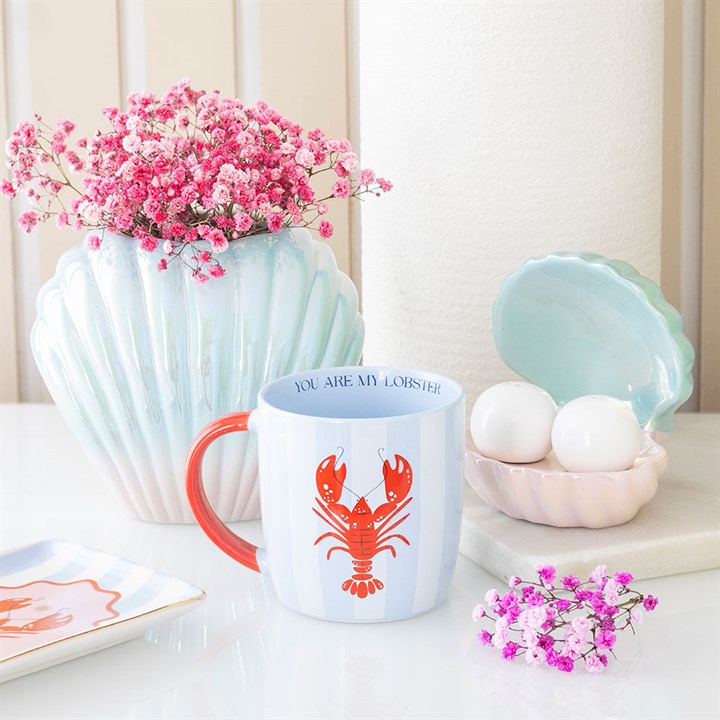 Mug with lobster design on a table with flowers and decorative items
