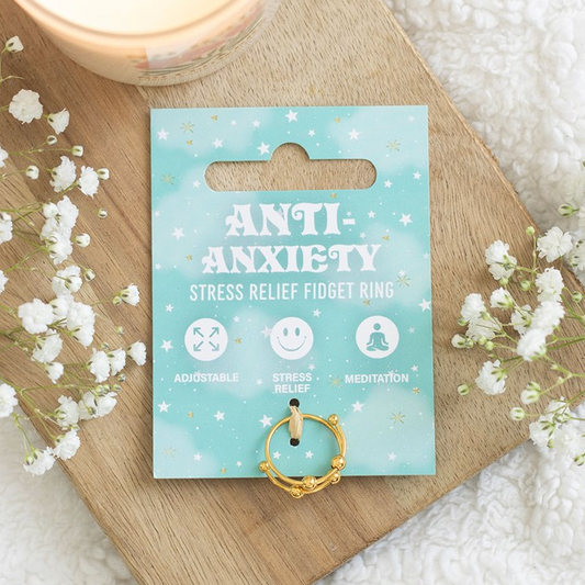 Anti-anxiety stress relief fidget ring packaging on a wooden board with flowers.