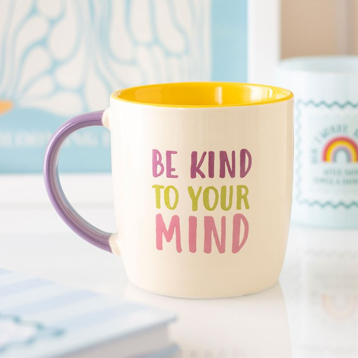 Mug with 'Be Kind to Your Mind' text on a blurred background