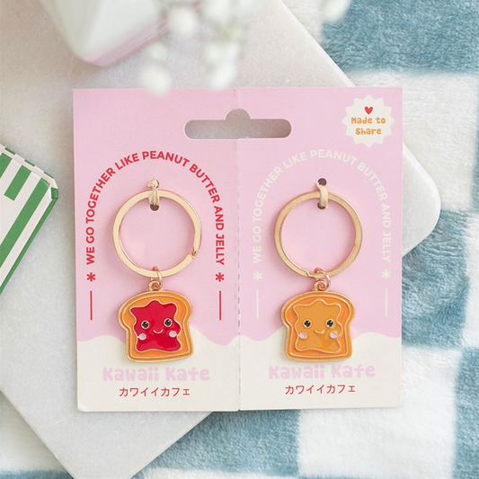 Pair of keychains shaped like peanut butter and jelly on a pink card with branding.