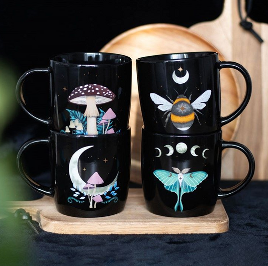 Set of black mugs with nature-themed designs on a wooden board.