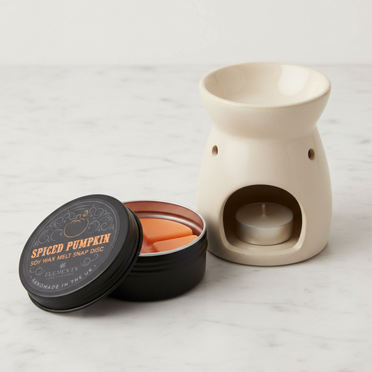 Spiced pumpkin wax melts in a black container with a ceramic warmer on a light gray background